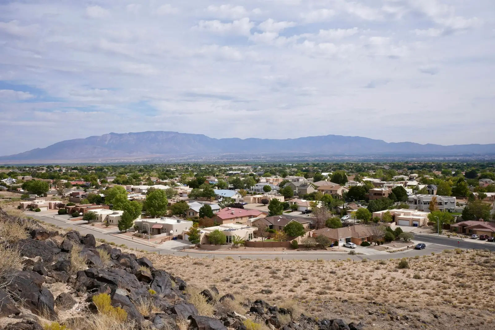 Albuquerque neighborhood of low stucco homes below the Sandia Mountains
