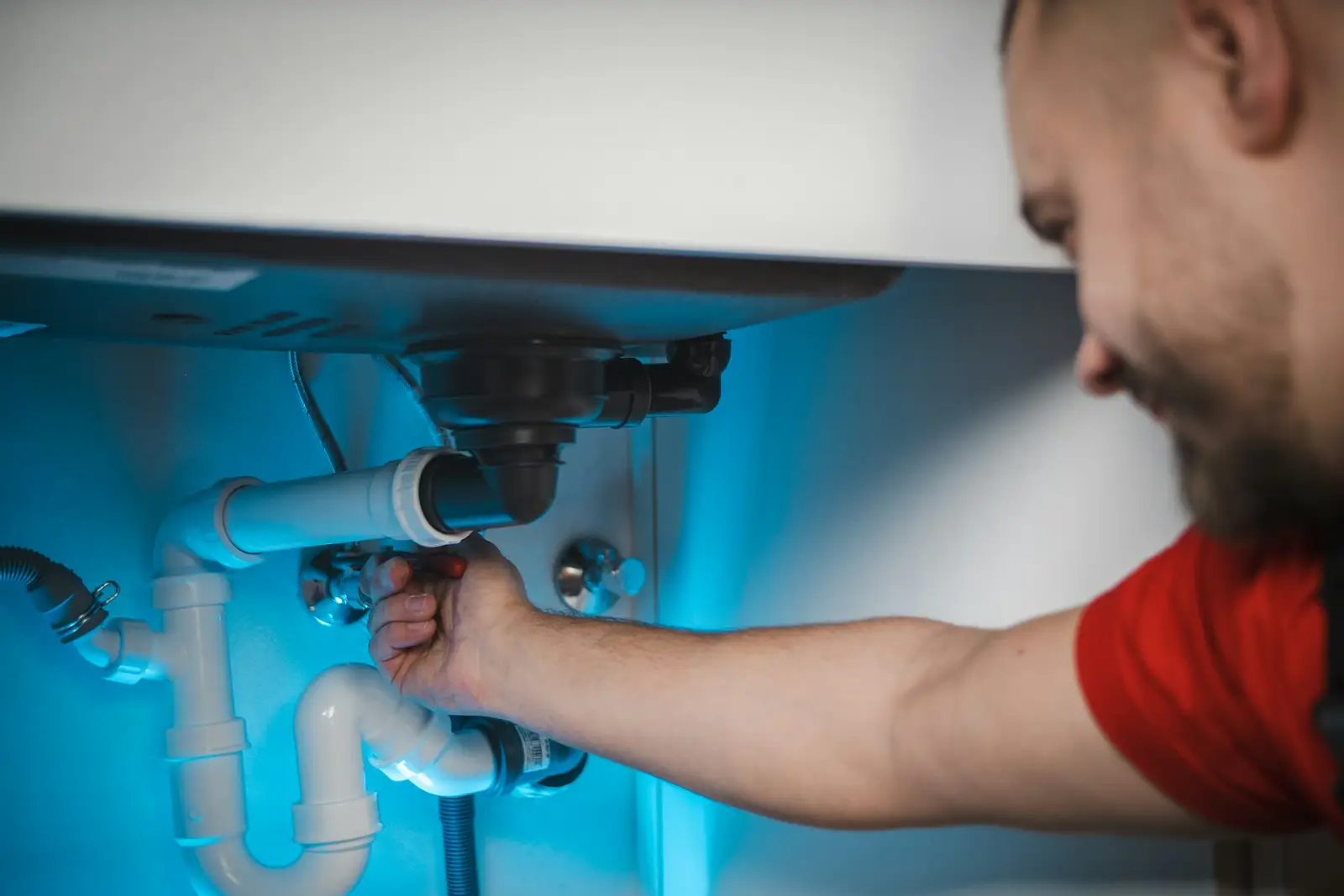 Plumber working on pipes under a sink